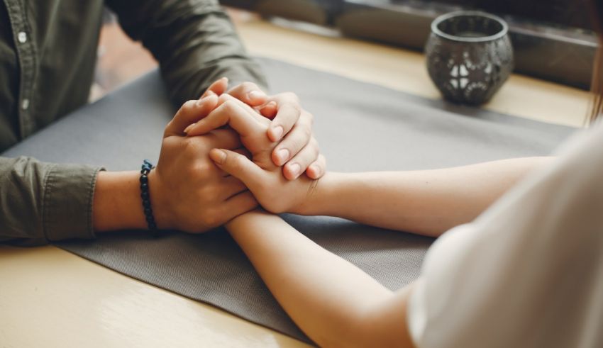 A man and woman holding hands on a table.