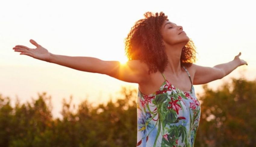 A woman with her arms outstretched at sunset.