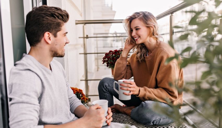 A man and woman sitting on a balcony talking to each other.