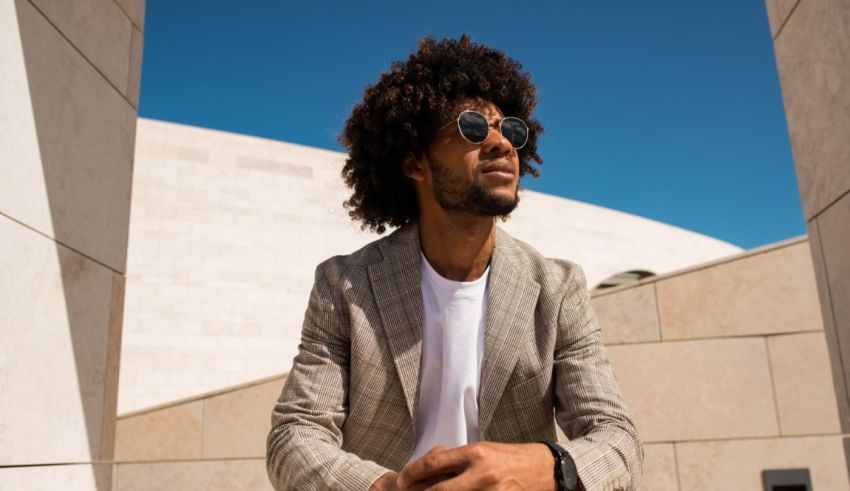 A young man with afro hair sitting on a stone wall.