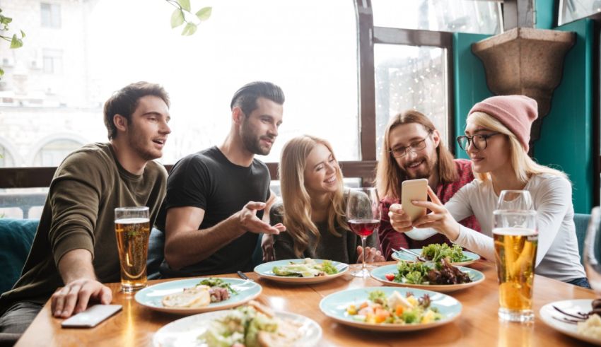A group of friends sitting at a table with food and drinks.