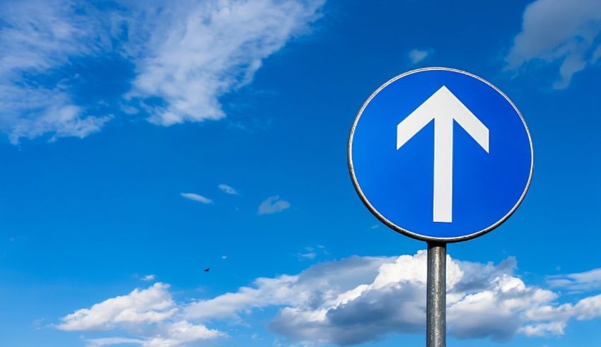 A blue road sign with an arrow pointing up.