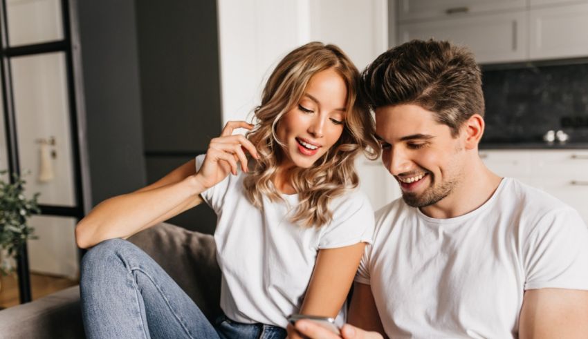 Young couple sitting on the couch and looking at their phone.