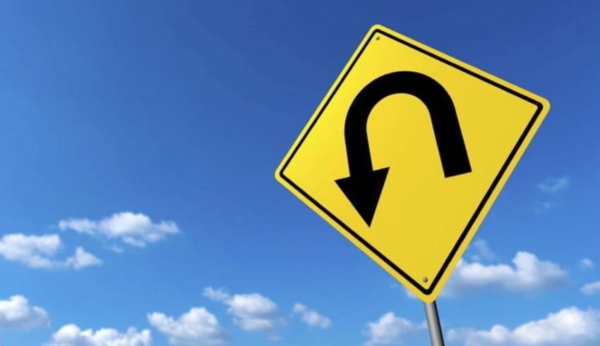 A road sign with a curved arrow against a blue sky.
