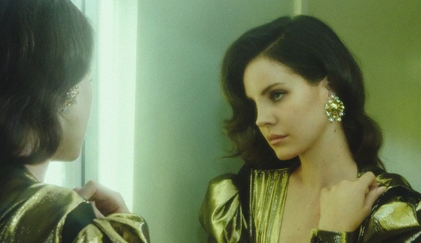 A woman in a gold dress looking at herself in the mirror.