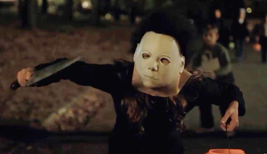 A woman dressed as michael myers is holding a knife.
