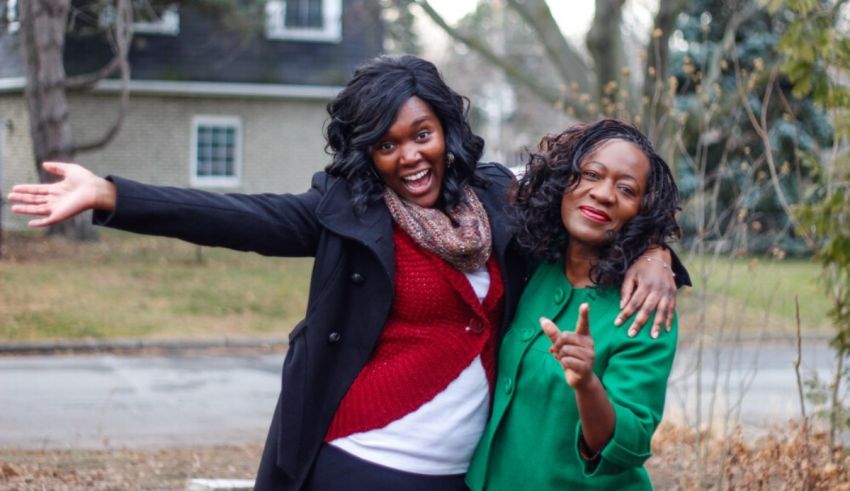 Two women posing for a picture in front of a house.