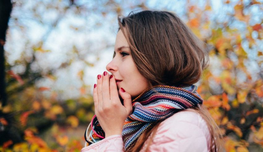 A woman wearing a scarf and holding her hand in front of her face.