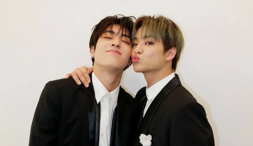 Two young men in suits posing for a picture.