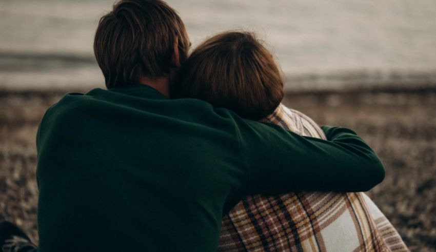A man and woman hugging on the beach.