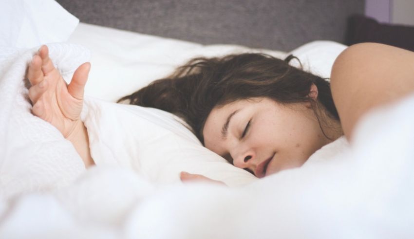 A woman is sleeping in a bed with white sheets.