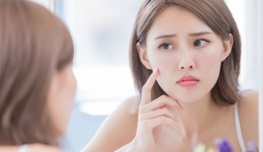 A woman is looking at her face in the mirror.
