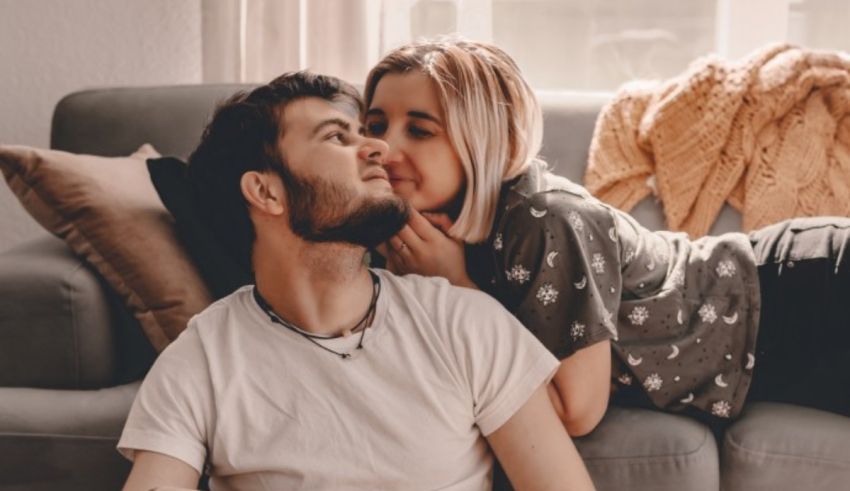 A man and woman kissing on a couch.