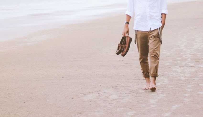 A man walking on the beach with a bag.