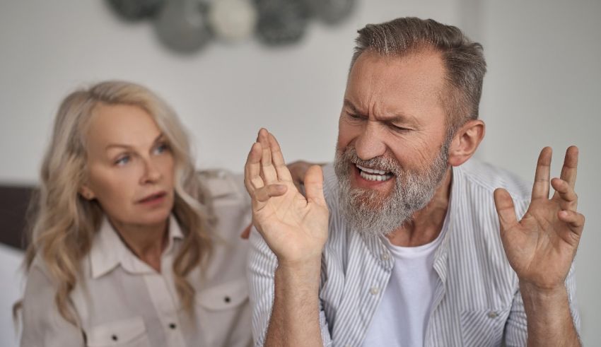 An older man and woman arguing in bed.