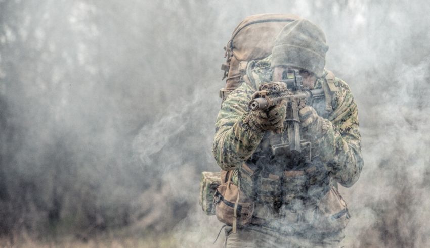 A soldier in a camouflage uniform is holding a rifle.