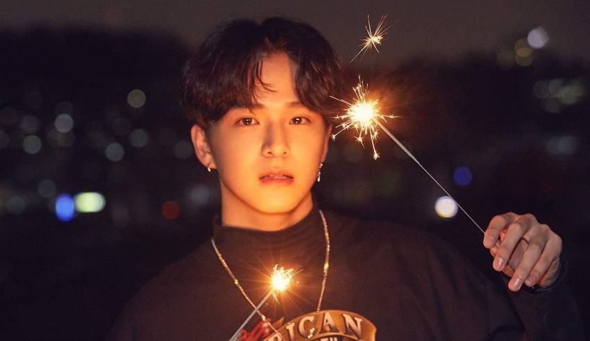 A young man holding sparklers in his hands.