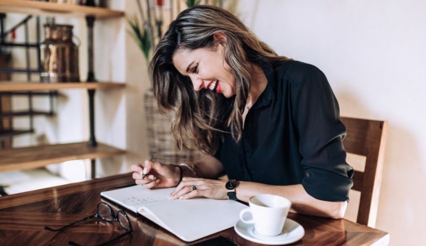 A woman writing on a notebook in a coffee shop.