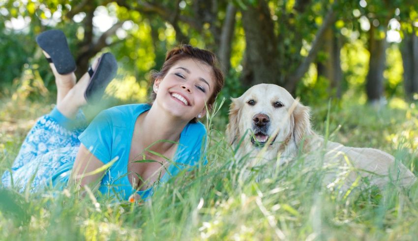 A woman laying in the grass with her dog.
