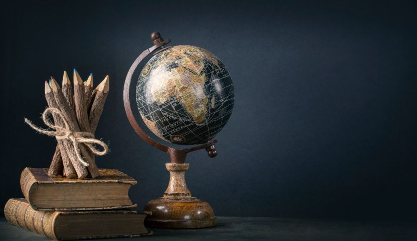 A globe, pencils and books on a dark background.