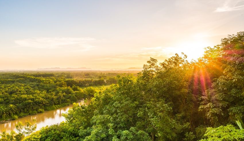 The sun is setting over a river in thailand.