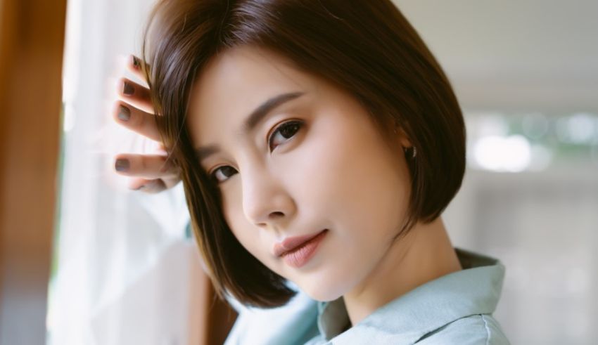 A young asian woman leaning against a window.