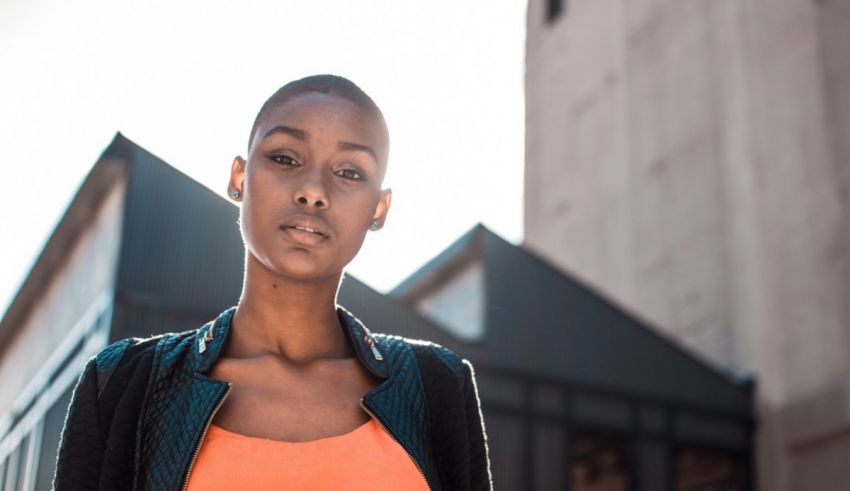 A young woman in an orange top standing in front of a building.