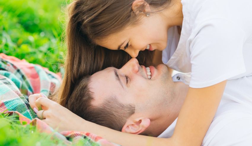 A man and woman laying on a blanket in the grass.