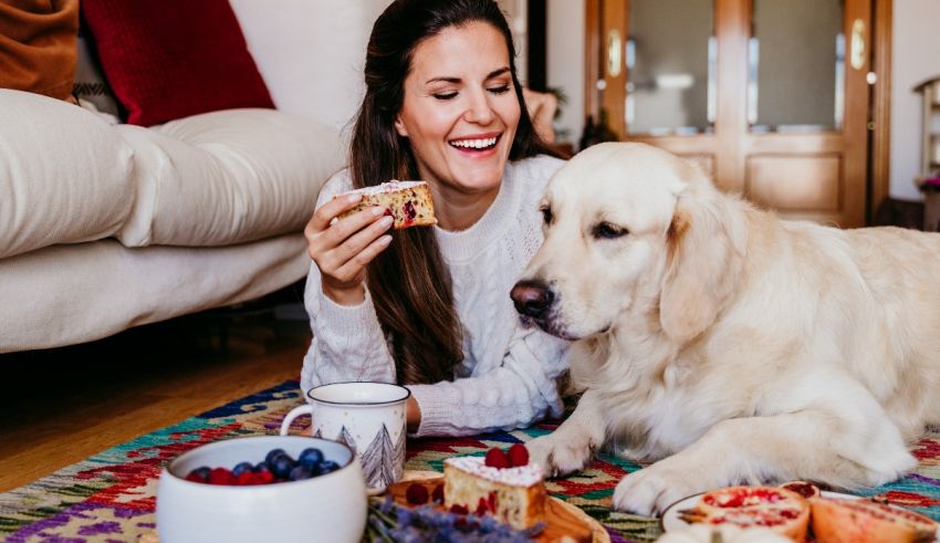 A woman laying on a rug with a golden retriever and a cake.