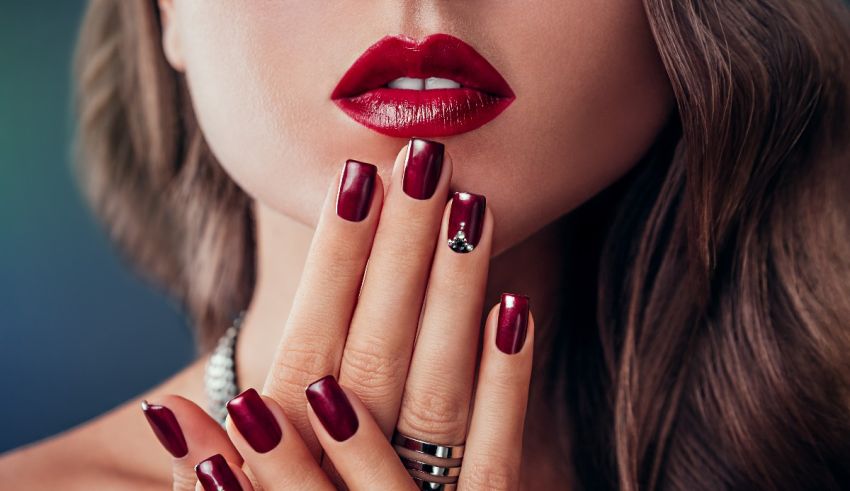 A woman with red nails and a ring on her hand.