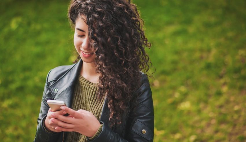 A young woman with curly hair looking at her phone.