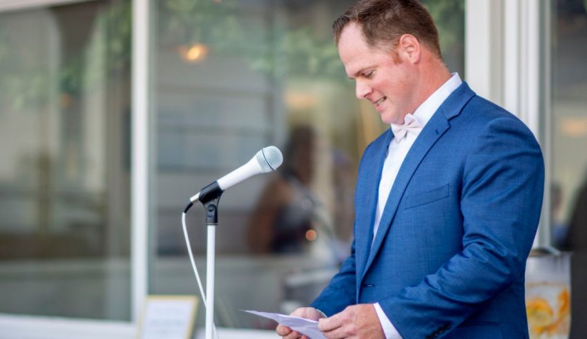 A man in a suit speaking into a microphone.