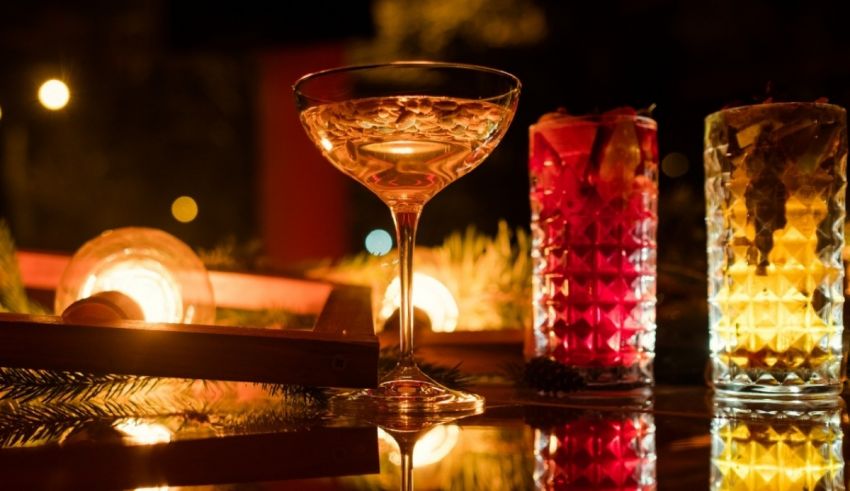 A glass of wine and a cocktail on a table at night.