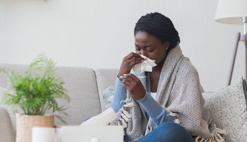 A woman blowing her nose while sitting on a couch.