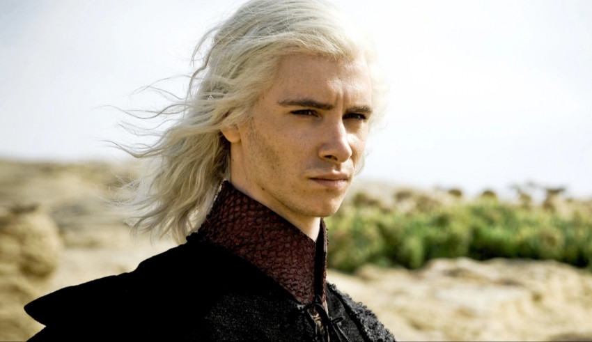 A man with white hair standing in a desert.