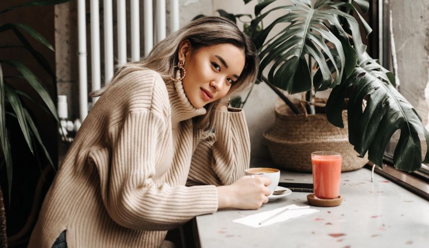 A woman sitting at a table with a cup of coffee.