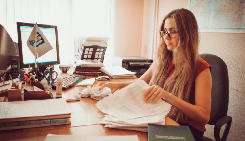 A woman sitting at a desk with papers and a computer.
