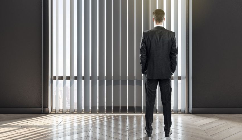 A man in a suit standing in front of a window.