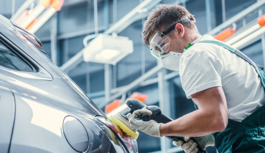 A man is polishing a car in a factory.