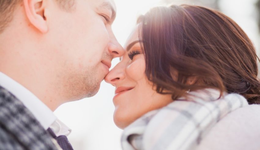 A man and woman are kissing each other in the snow.