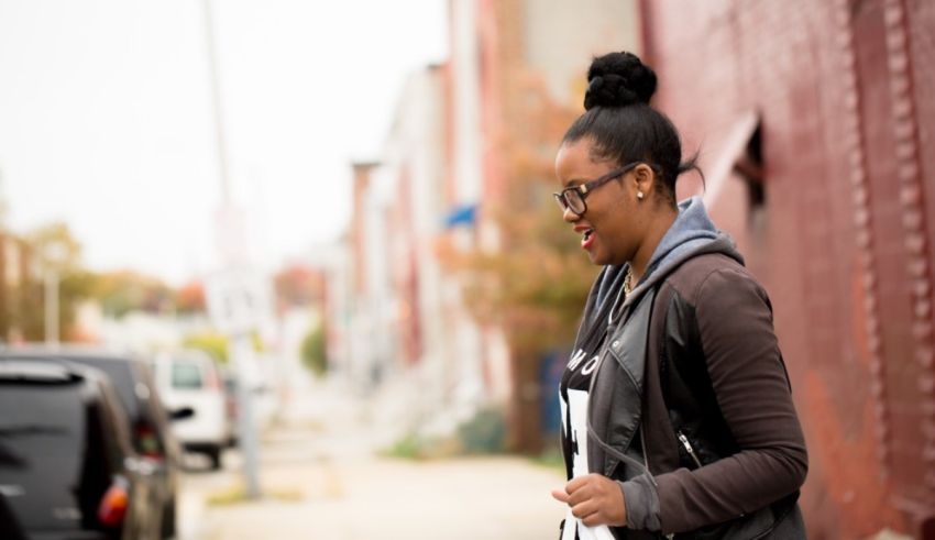 A young woman walking down a street with a cell phone.