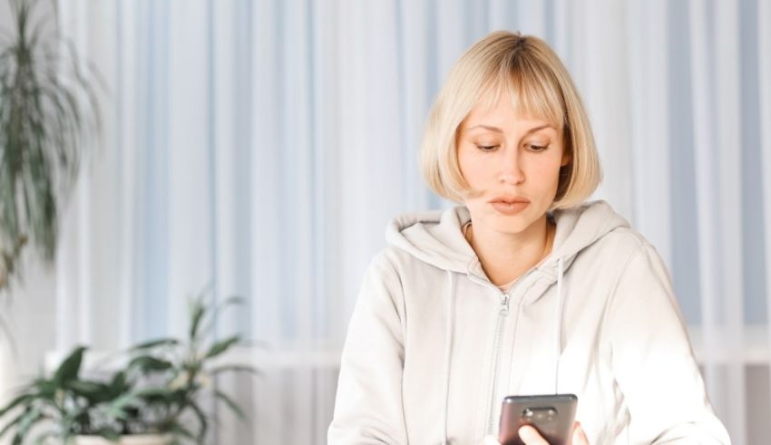 A woman is sitting at a table looking at her phone.