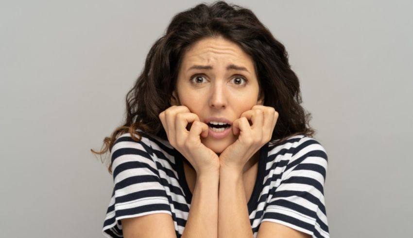 A woman in a striped shirt with her hands on her face.