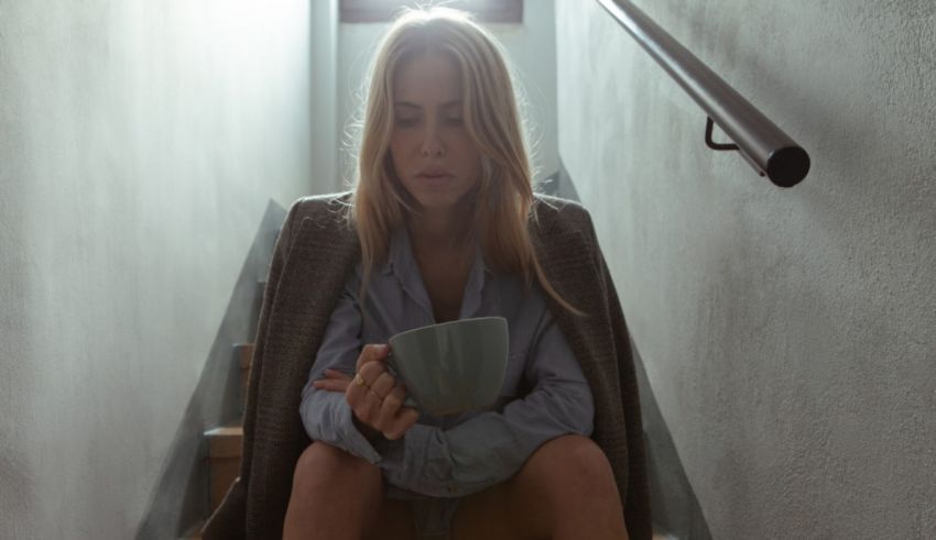A woman sitting on stairs holding a cup.