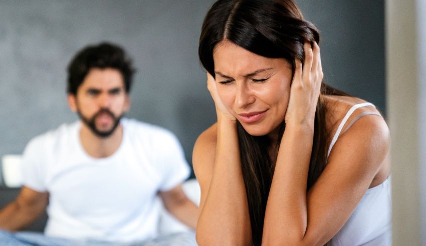 A woman is holding her ear while a man is looking at her.