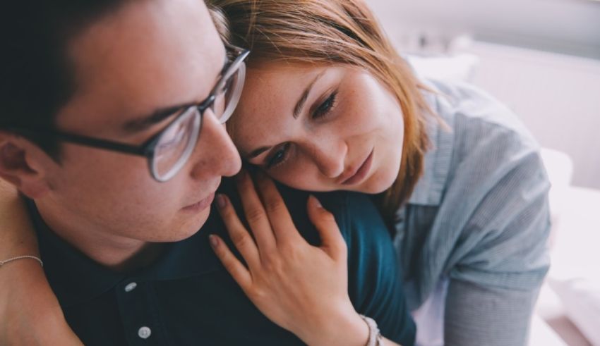 A young man and woman hugging each other at home.