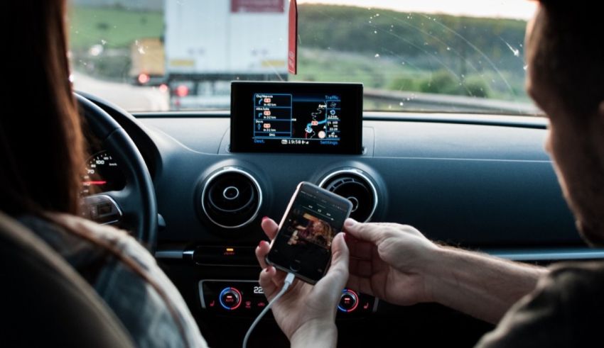 A man and woman in a car using a cell phone.