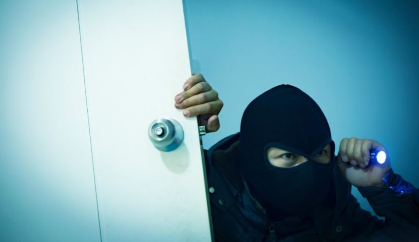 A thief in a mask is hiding behind a door.