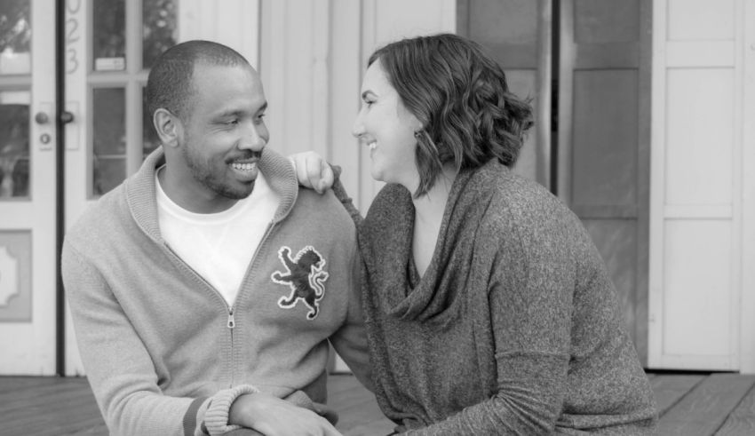 A black and white photo of a couple sitting on a porch.