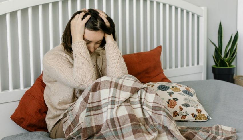 A woman sitting on a bed with her head in her hands.